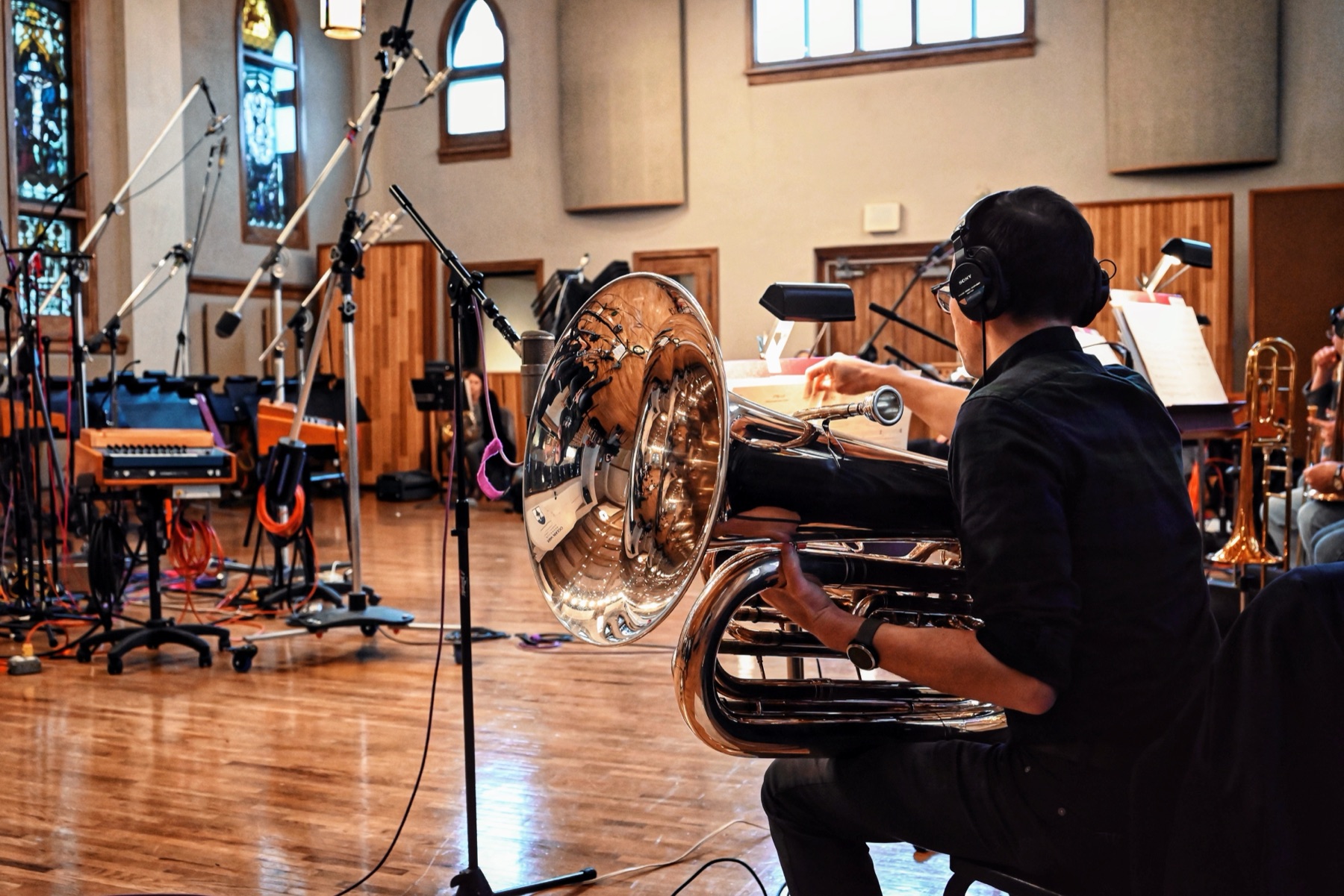Neil, wearing headphones, playing a large silver tuba during an orchestral recording session